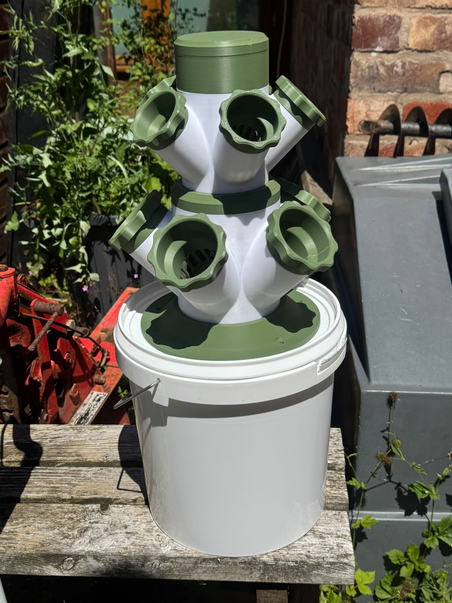 Full real product photo of HERB modular hydroponic tower on a bucket outdoors